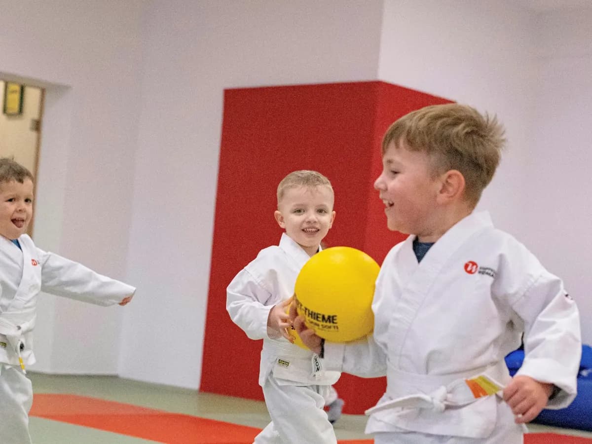 Zwei lachende Jungs üben mit einem gelben Ball